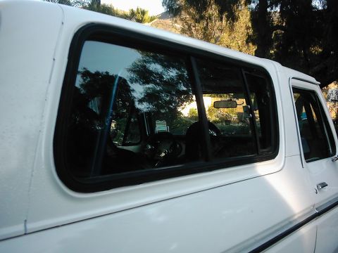 1978 Ford Bronco - The side profile of a white 1978 Ford Bronco reveals its interior and tinted windows.