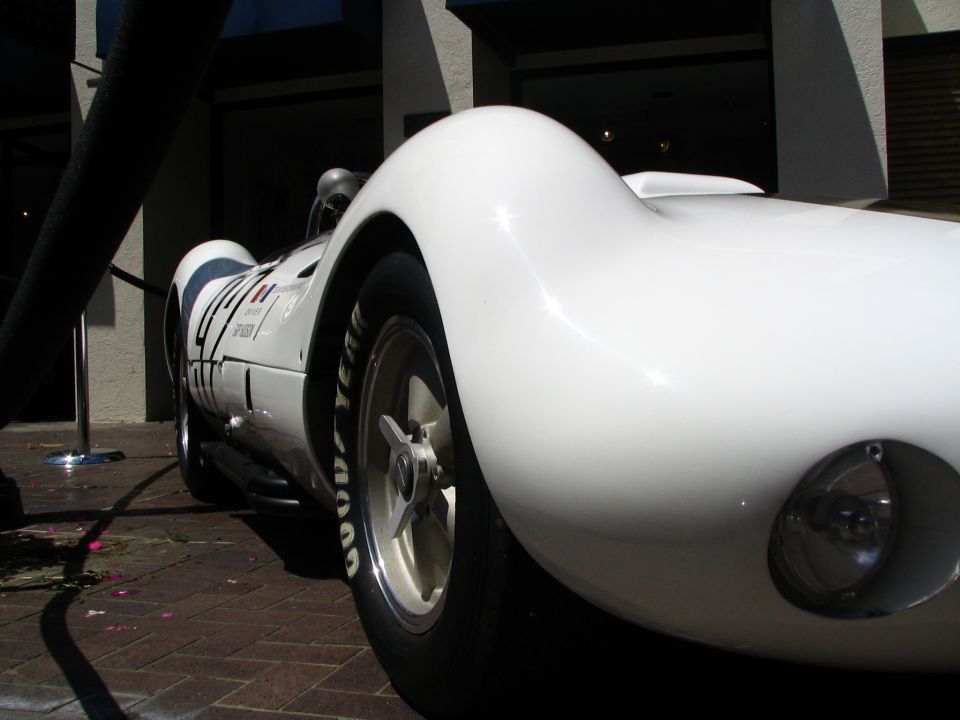 Low rear view of a white vintage race car with pontoon fender, Goodyear tires and knock-off wheel