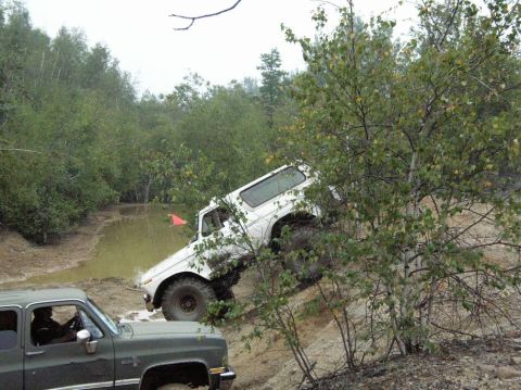 1995 Ford Bronco - A white Ford Bronco navigates a challenging off-road course, with another vehicle partially visible.