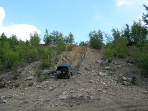 1995 Ford Bronco - A black SUV navigates a challenging off-road trail on a sunny day.