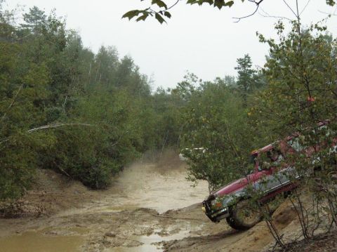 1995 Ford Bronco - A red 1995 Ford Bronco navigates a challenging muddy terrain during an off-road excursion.