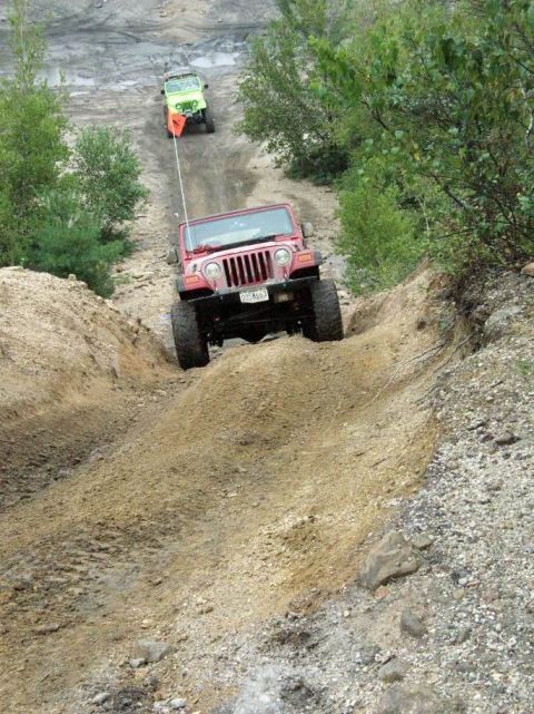 1995 Ford Bronco - An ATV navigates a steep dirt incline surrounded by greenery.