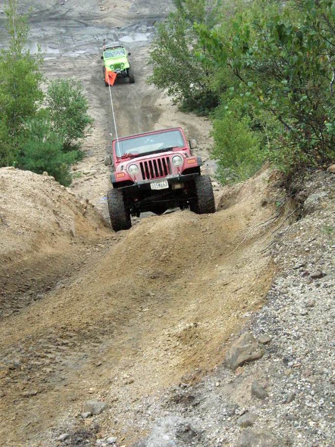 ATV driving up a dirt hill with trees in the background