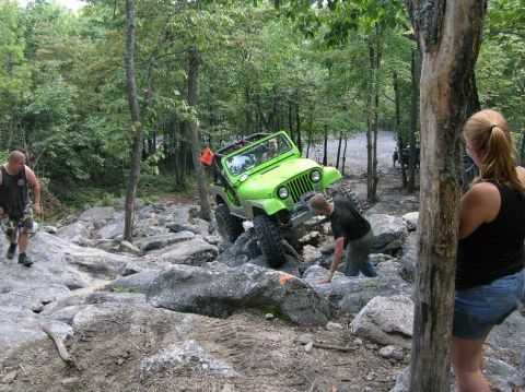 1995 Ford Bronco - Off-road enthusiasts tackle a challenging rocky course in a bright green Jeep Wrangler.