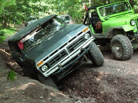 1995 Ford Bronco - A Ford truck is stuck in a ditch while a green Jeep watches nearby on a wooded trail.