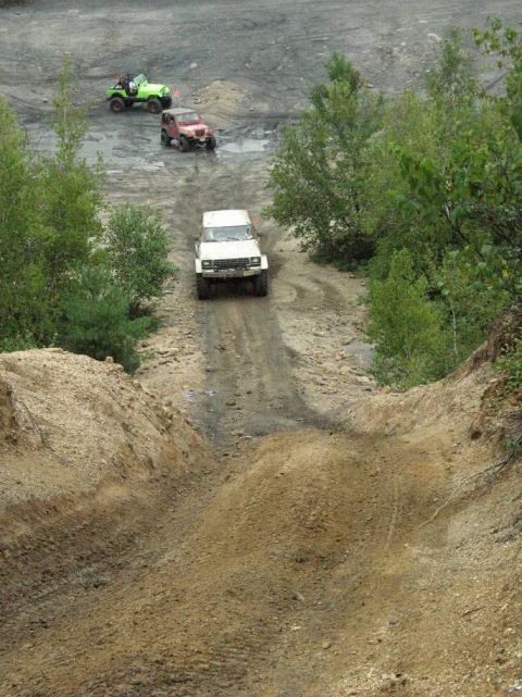 1995 Ford Bronco - Multiple off-road vehicles navigate a challenging dirt terrain, with one white SUV prominently in the foreground.