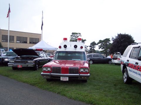 2001 Ford Crown Victoria - An older model ambulance is displayed alongside other vehicles at an outdoor event.