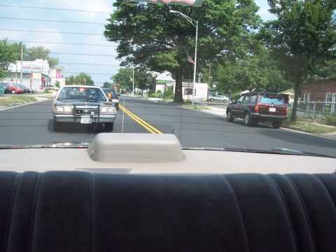 2001 Ford Crown Victoria - A 2001 Ford Crown Victoria police car is seen from the rear seat of another vehicle on a sunny day.