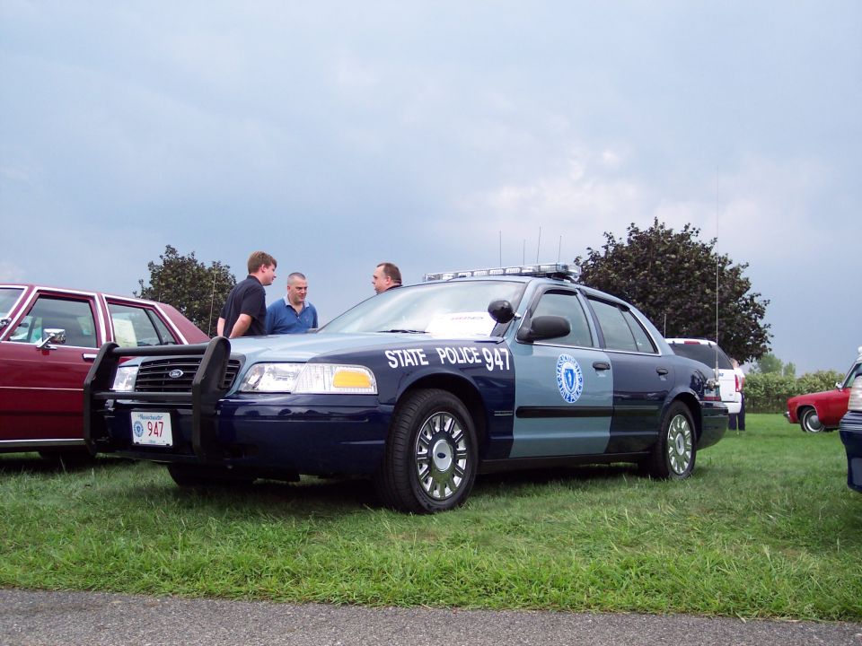 Blue and grey 2001 Ford Crown Victoria police car with "STATE POLICE 947" text, parked on grass