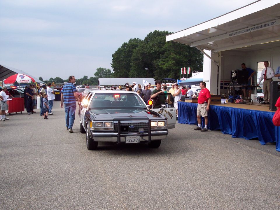 Black police car with "WAY PATROL" text on door, front view
