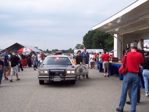 2001 Ford Crown Victoria - Police car with flashing lights and people gathered around at an outdoor event.