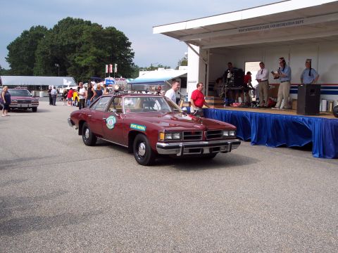 2001 Ford Crown Victoria - A vintage state patrol car is shown in front of a stage with people gathered.
