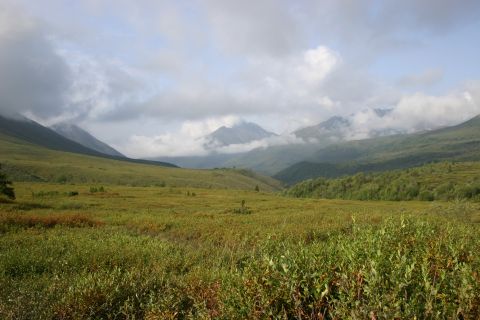 2003 Jeep TJ - A vast mountain landscape under a cloudy sky, with rolling green hills and fields in the foreground.