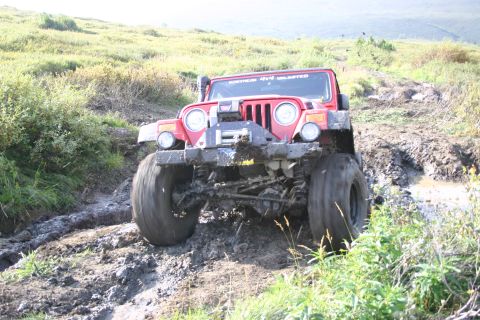 2003 Jeep TJ - Red Jeep Wrangler navigates a challenging muddy off-road course.