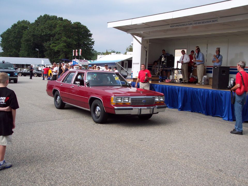 Red sedan with chrome grille and bumper, seen from a 3/4 front angle