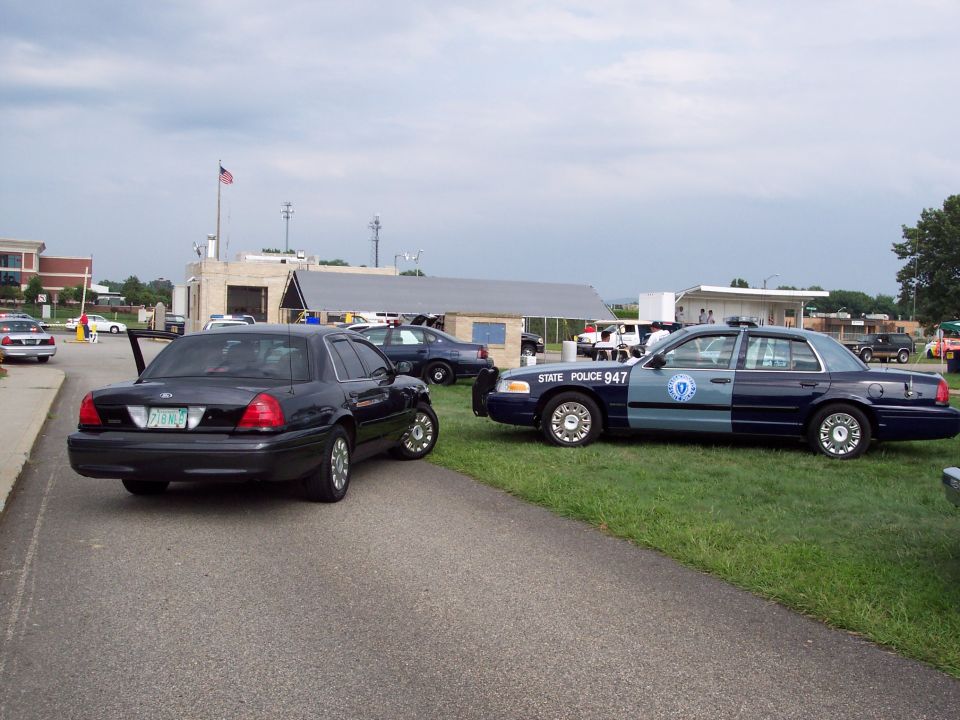 Dark 2001 Ford Crown Victoria and a blue and dark blue police car parked on grass