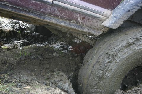 2003 Jeep TJ - Vehicle stuck deep in mud, showing the tire and undercarriage.