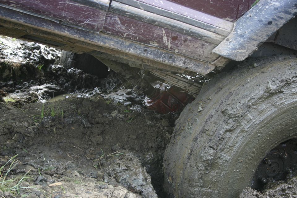 Muddy tire and undercarriage of a vehicle stuck in deep mud
