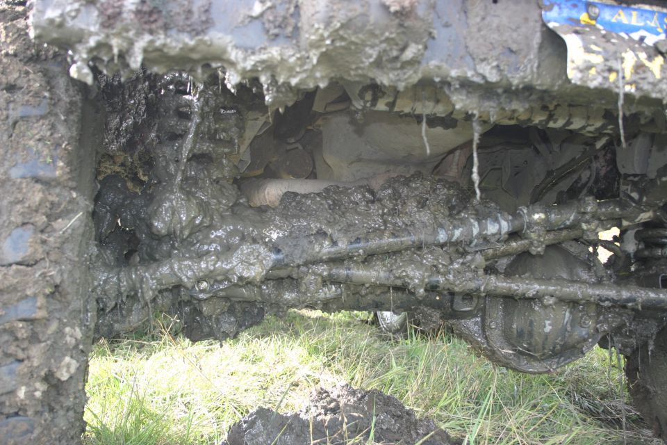 Mud-caked undercarriage with visible suspension and steering components