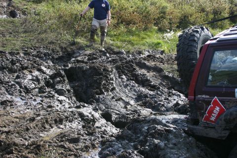 2003 Jeep TJ - Off-road vehicle stuck in mud, with a person nearby holding a shovel.