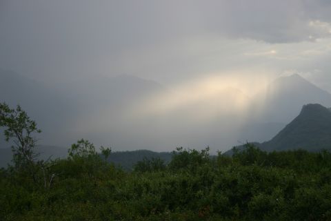 2003 Jeep TJ - Sunbeams pierce through clouds over a misty mountain landscape with dense green foliage in the foreground.