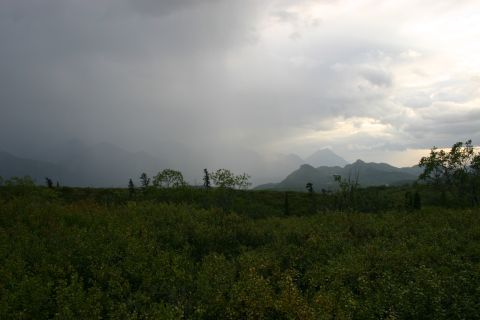 2003 Jeep TJ - A vast landscape under a stormy sky, with mountains in the distance and dense vegetation in the foreground.