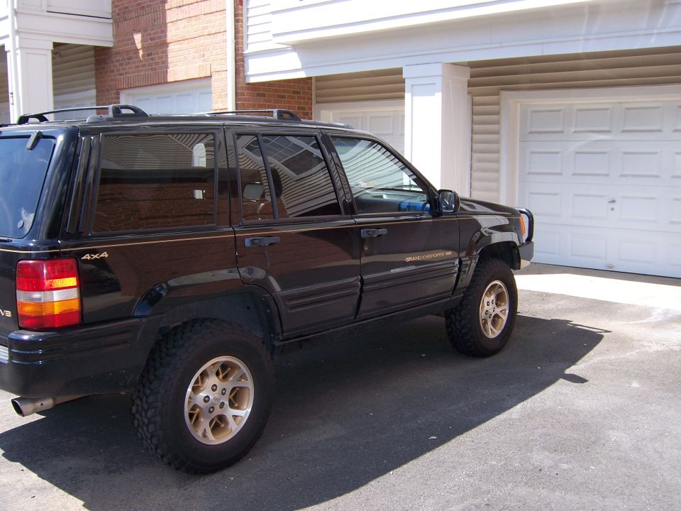 Black Jeep Grand Cherokee parked in front of a garage