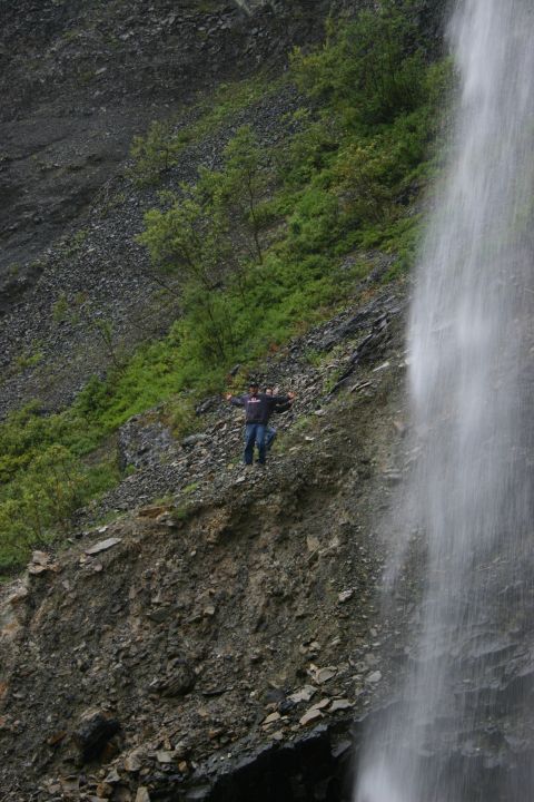 2003 Jeep TJ - A person stands on a steep, rocky incline near a cascading waterfall.