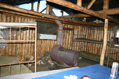 2003 Jeep TJ - Rustic cabin interior features bunk beds and a central wood-burning stove for warmth.