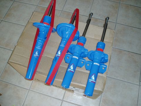 1993 Ford Taurus - Four blue Tokico struts with red straps are laid out on a cardboard box, ready for installation.