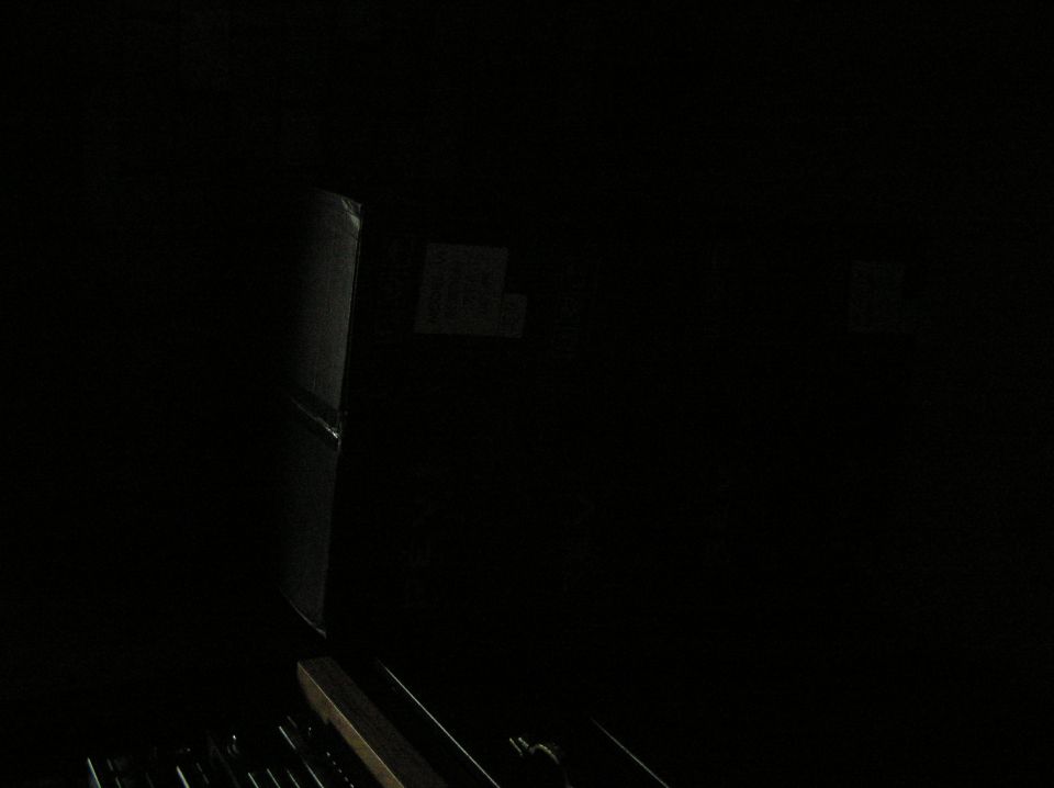 Very dark underexposed shot showing faint outline of cardboard boxes in a dim space