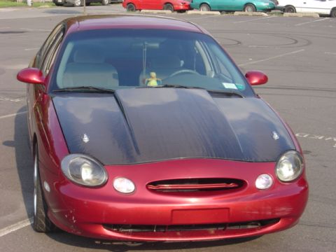 1998 Ford Taurus - A red 1998 Ford Taurus is shown from the front, an aftermarket hood.
