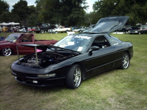 1995 Ford Probe - A black 1995 Ford Probe is displayed with its hood and rear hatch open at an outdoor car show.