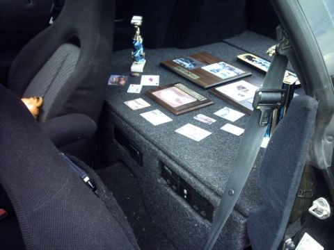 1995 Ford Probe - The interior of a vehicle is shown, seats and a custom carpeted area with awards and cards.