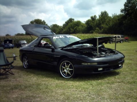 1995 Ford Probe - A black 1995 Ford Probe is parked on a grassy field with its hood and trunk open, showing off the engine and interior.