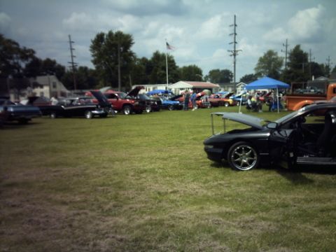 1995 Ford Probe - A gathering of cars on a grassy field under a cloudy sky.