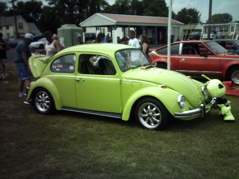 1995 Ford Probe - A lime green Volkswagen Beetle is parked on grass with a stuffed alien attached to its front bumper.