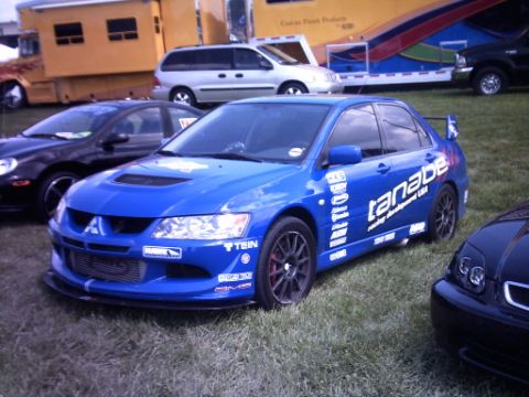 1995 Ford Probe - Blue Mitsubishi Lancer Evolution with racing decals is parked next to other vehicles at an event.