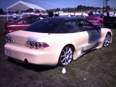 1995 Ford Probe - A customized coupe, unfinished in primer, sits on the grass at an outdoor car show.