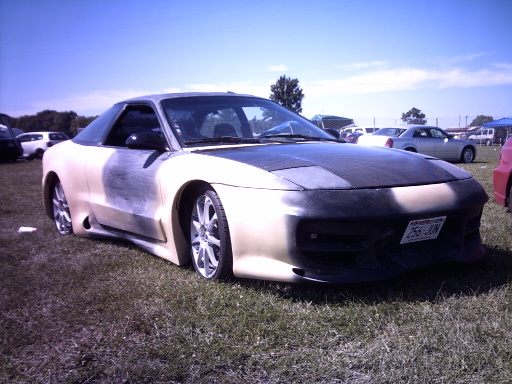 Primered Ford Probe with body kit and smoothed front bumper on grass at a car show