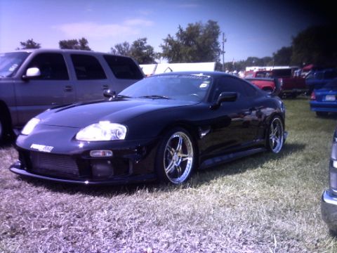 1995 Ford Probe - A black sports car is parked on grass at an outdoor event, with other vehicles visible in the background.