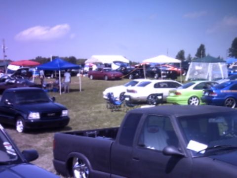 1995 Ford Probe - Multiple vehicles and tents are visible at an outdoor event on a sunny day.