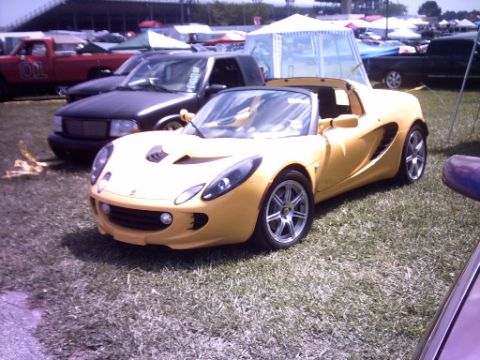 1995 Ford Probe - A yellow convertible sports car is parked on grass at an outdoor event.