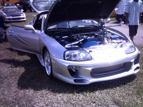1995 Ford Probe - Modified Toyota Supra on display at an outdoor car show, with hood and door open.
