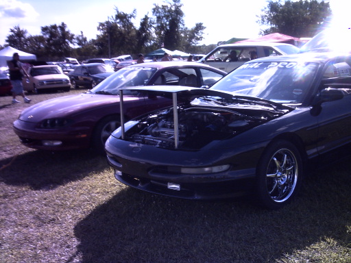 Black 1995 Ford Probe with hood open, parked next to a red car
