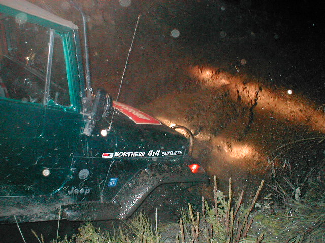 Green Jeep at night off-road with hood decal reading Northern 4x4 Suppliers, headlights lighting a dirt bank