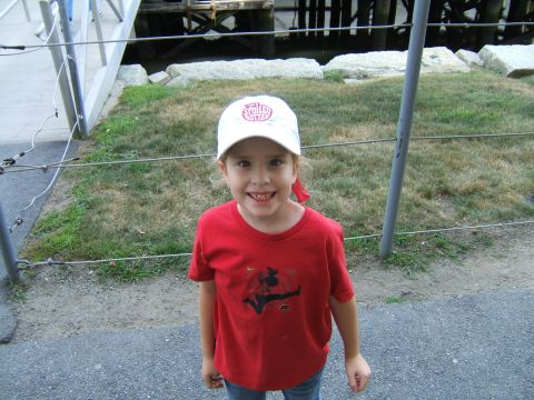 1998 Ford Taurus - A young child stands outdoors, wearing a red t-shirt and a white baseball cap with red lettering.