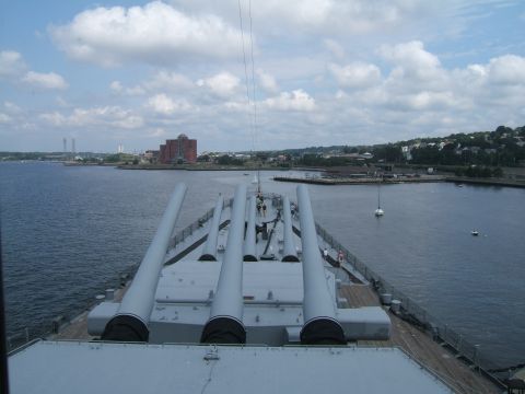 1998 Ford Taurus - View from a battleship deck, showing large guns and a harbor with buildings and a sailboat in the distance.