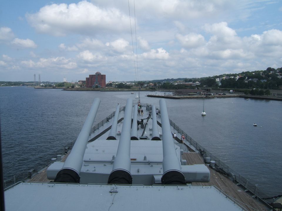 Battleship deck with large guns overlooking a harbor