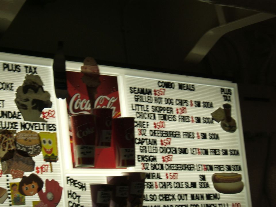 Menu board with combo meals like Seaman $3.57 and Little Skipper $3.80, plus Coca-Cola branding